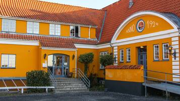 A yellow building with a red-tiled roof and a sign reading "Anno 1924".