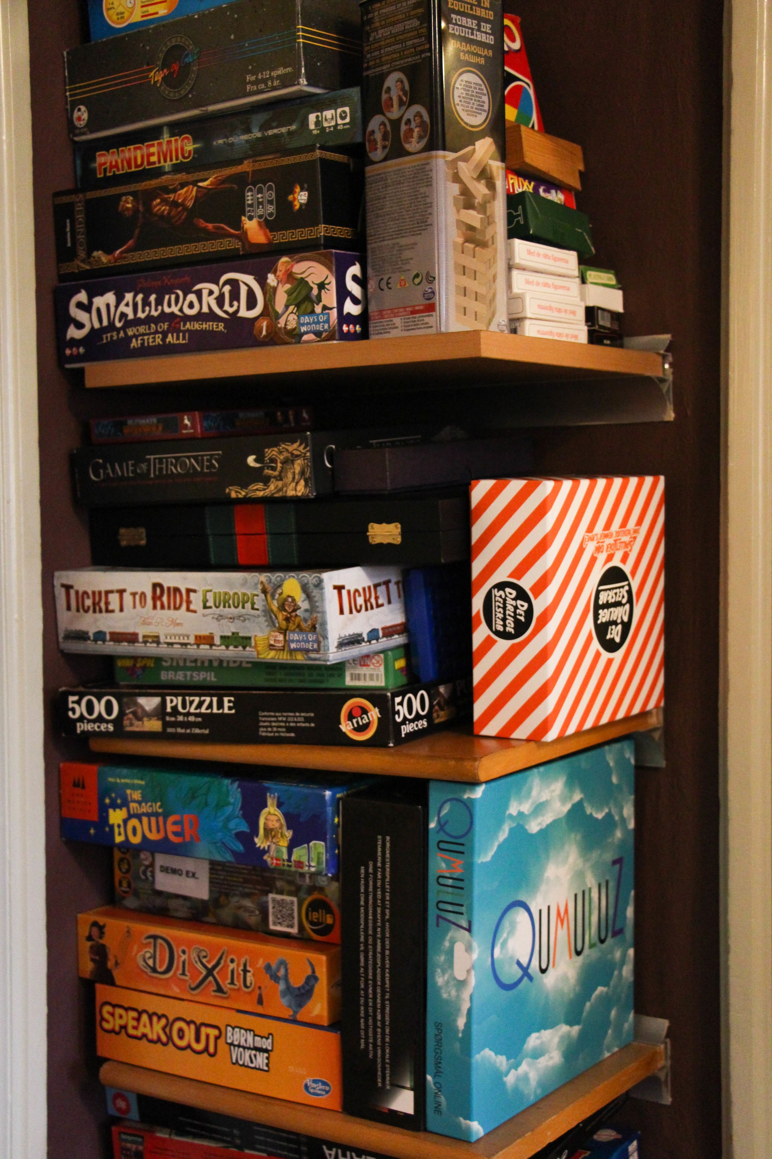 A shelf with various board games stacked on it.