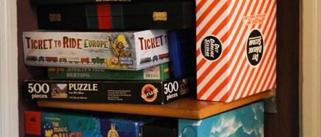 A shelf with various board games stacked on it.