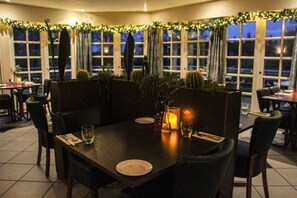 A dimly lit restaurant with a dark wooden table set for two, surrounded by chairs. - Krebshuset & Kelz0rdk (Soro)