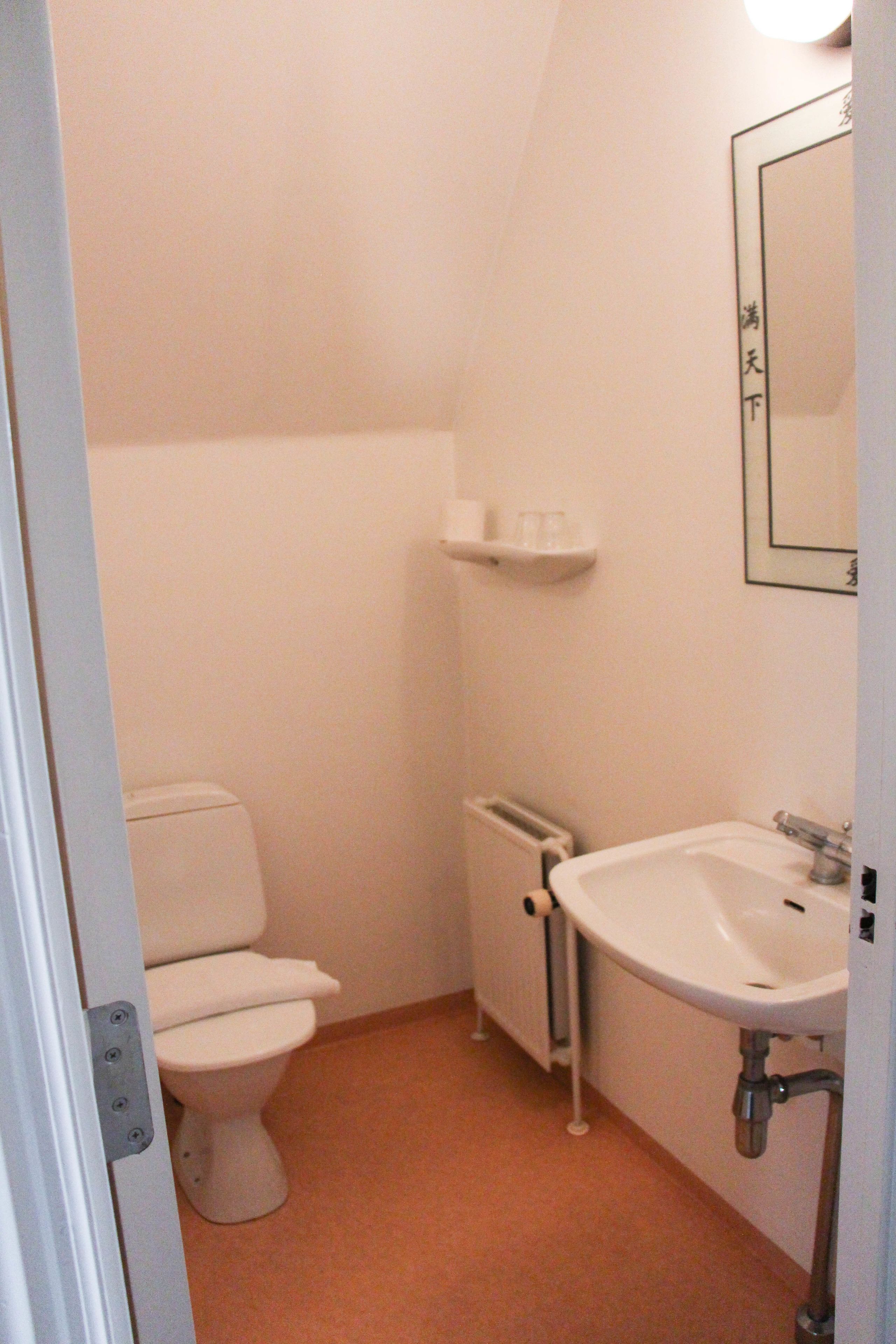 A small, white bathroom with a toilet, sink, and a mirror on the wall.