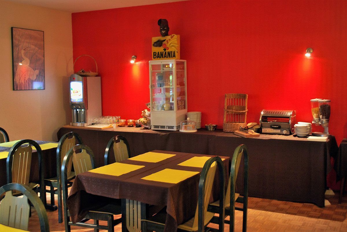 A dining area with tables and chairs, a refrigerator, a coffee machine, and a sign reading "BANANIA".