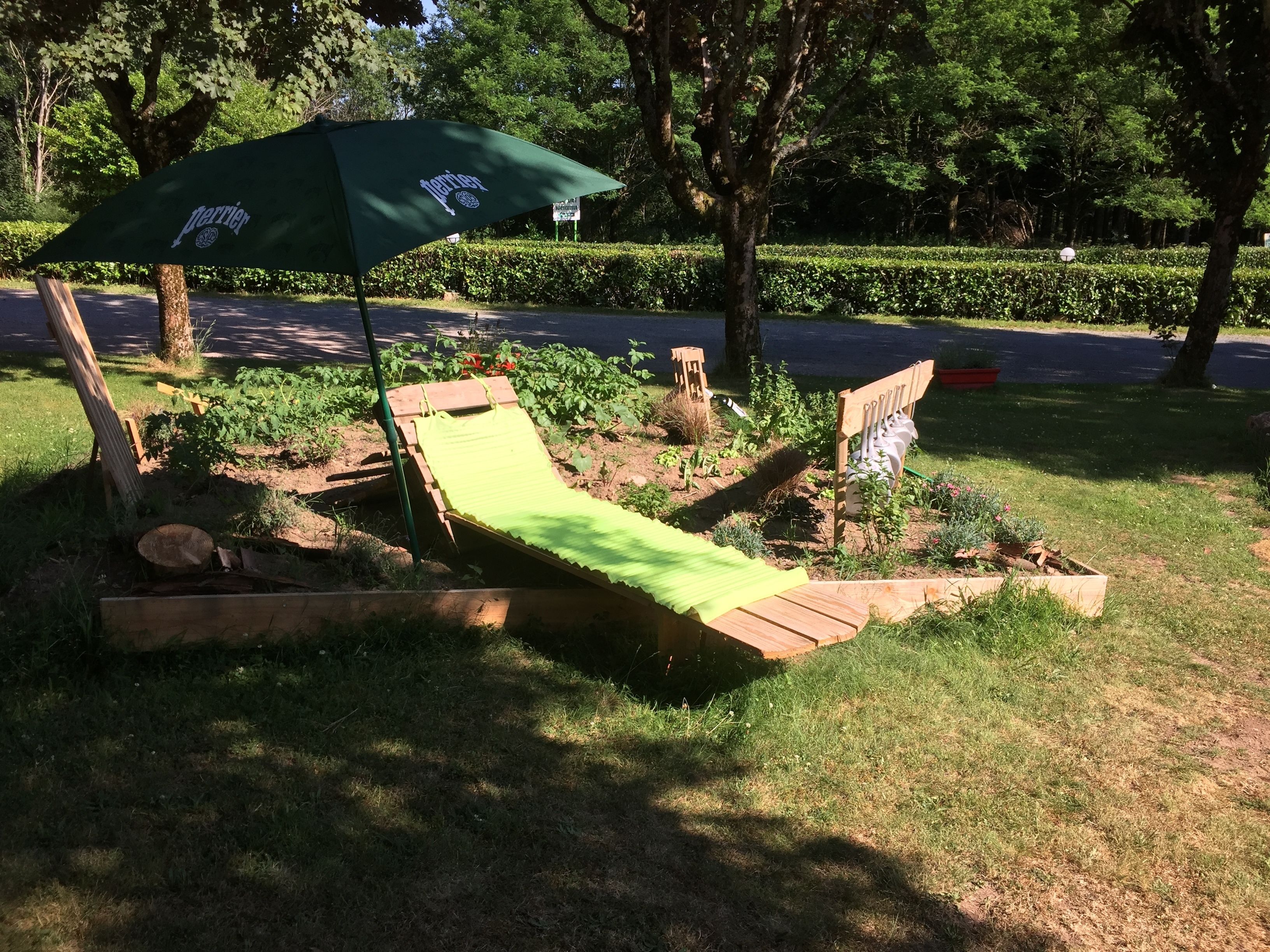 A wooden deck with a green lawn chair and a green umbrella.