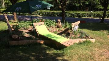 A wooden deck with a green lawn chair and a green umbrella.
