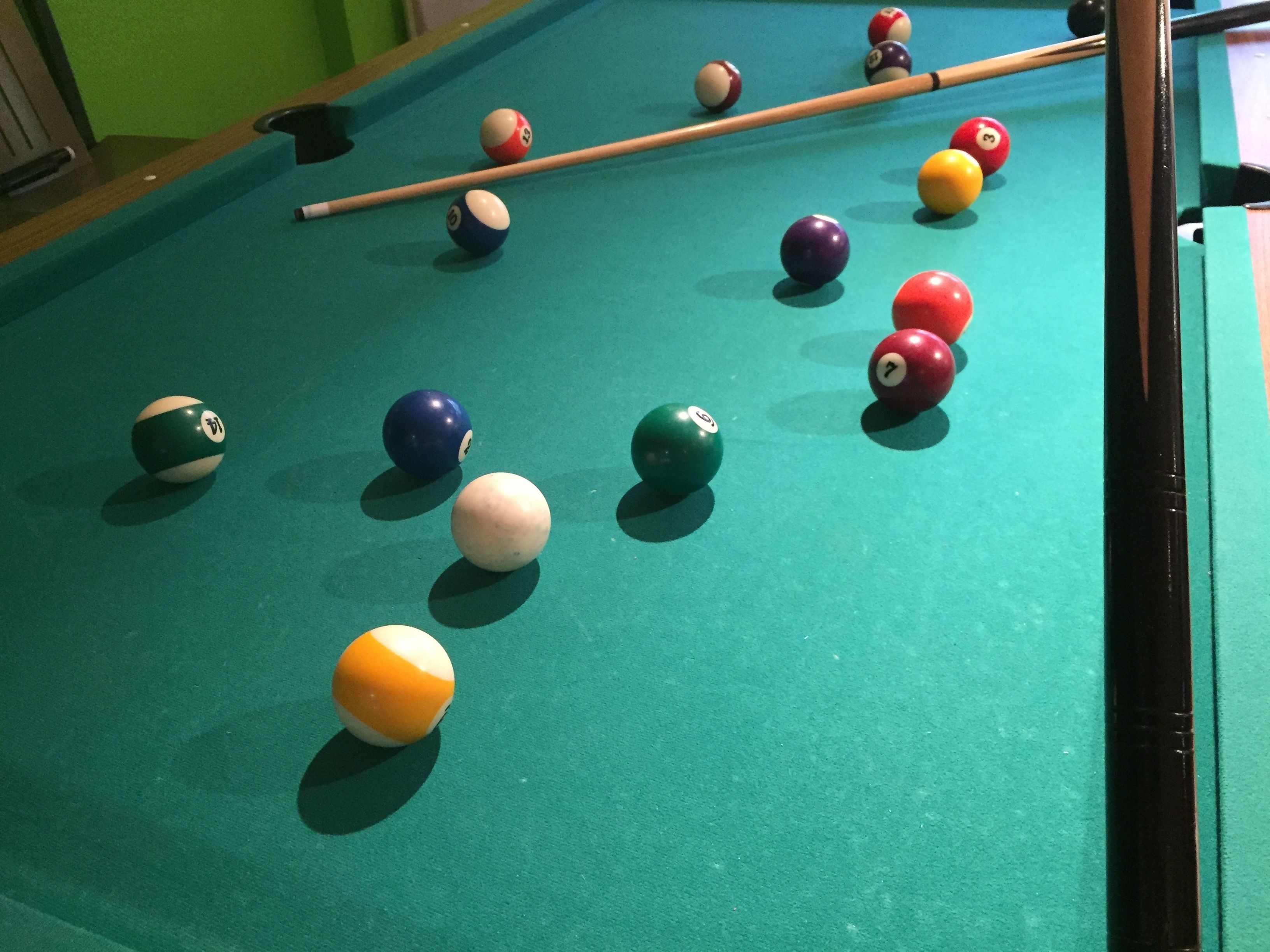 A pool table with various colored balls and a pool cue.