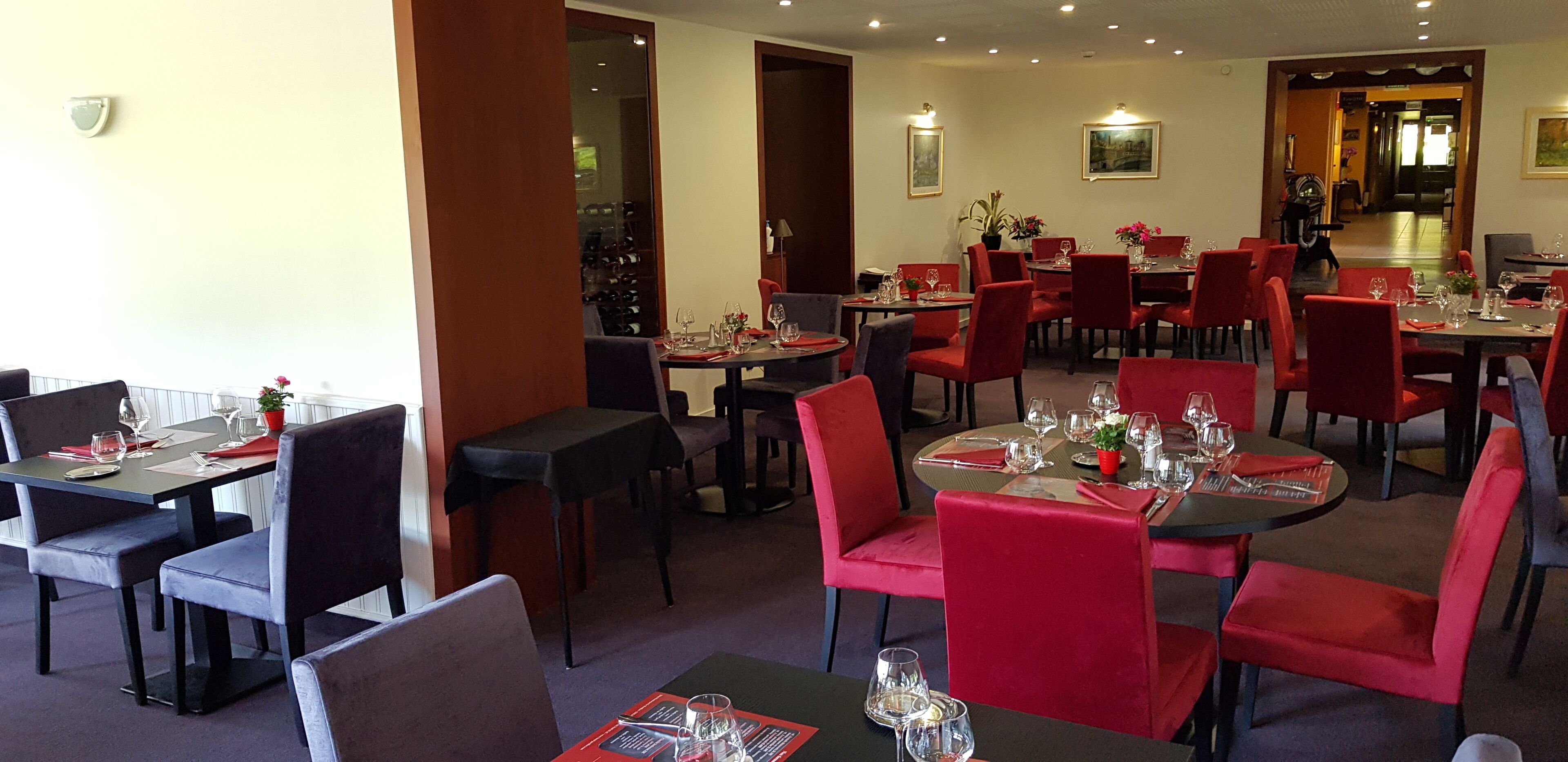 Un restaurante con varias mesas y sillas, algunas con tapicería roja.