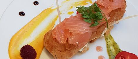 Un plato con un pastel, salmón y guarniciones.