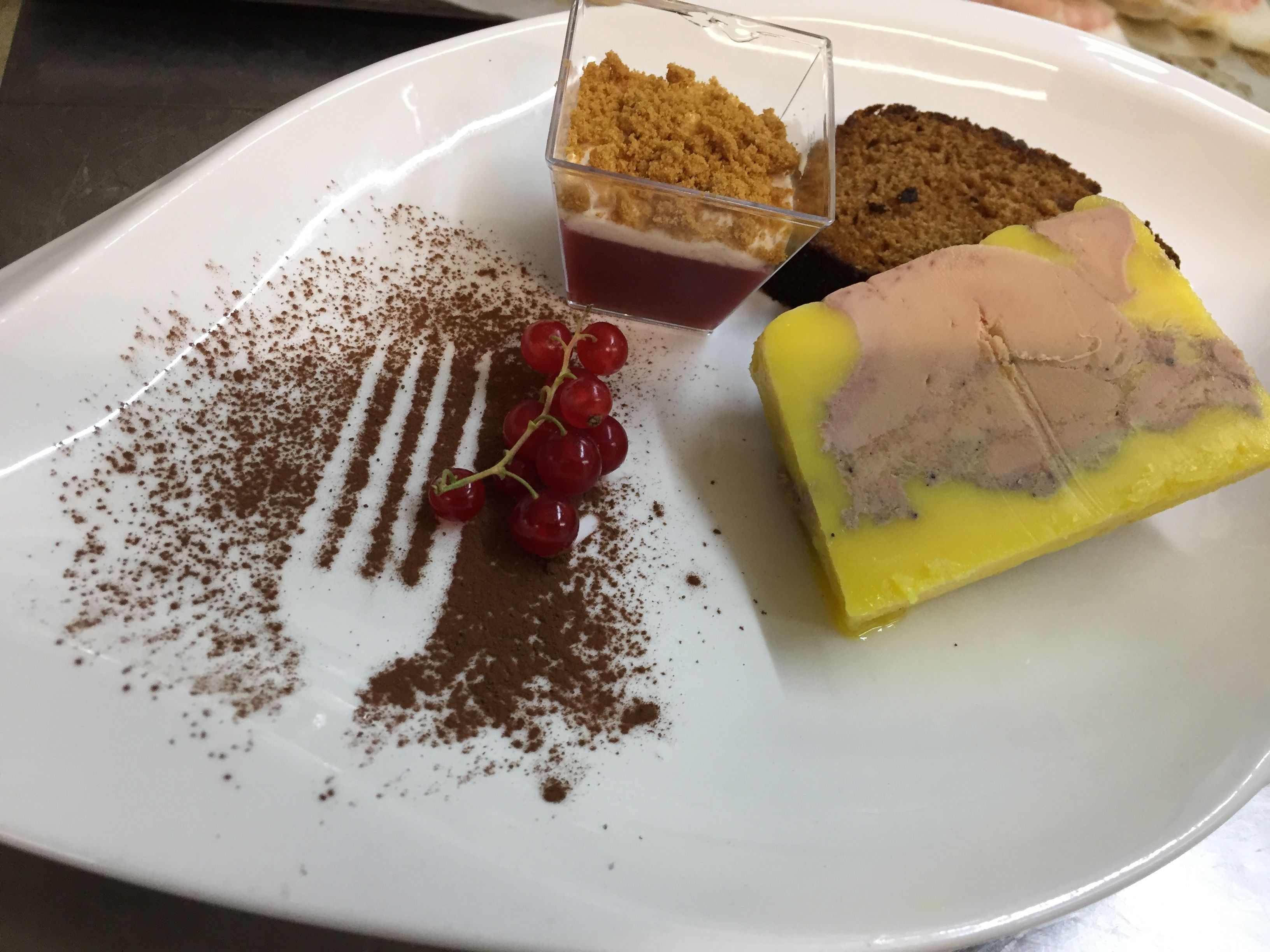A dessert plate with a slice of yellow cake topped with a pink cream and a piece of chocolate cake.