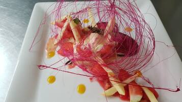 A white plate with a salad, including apple slices and a decorative red net.