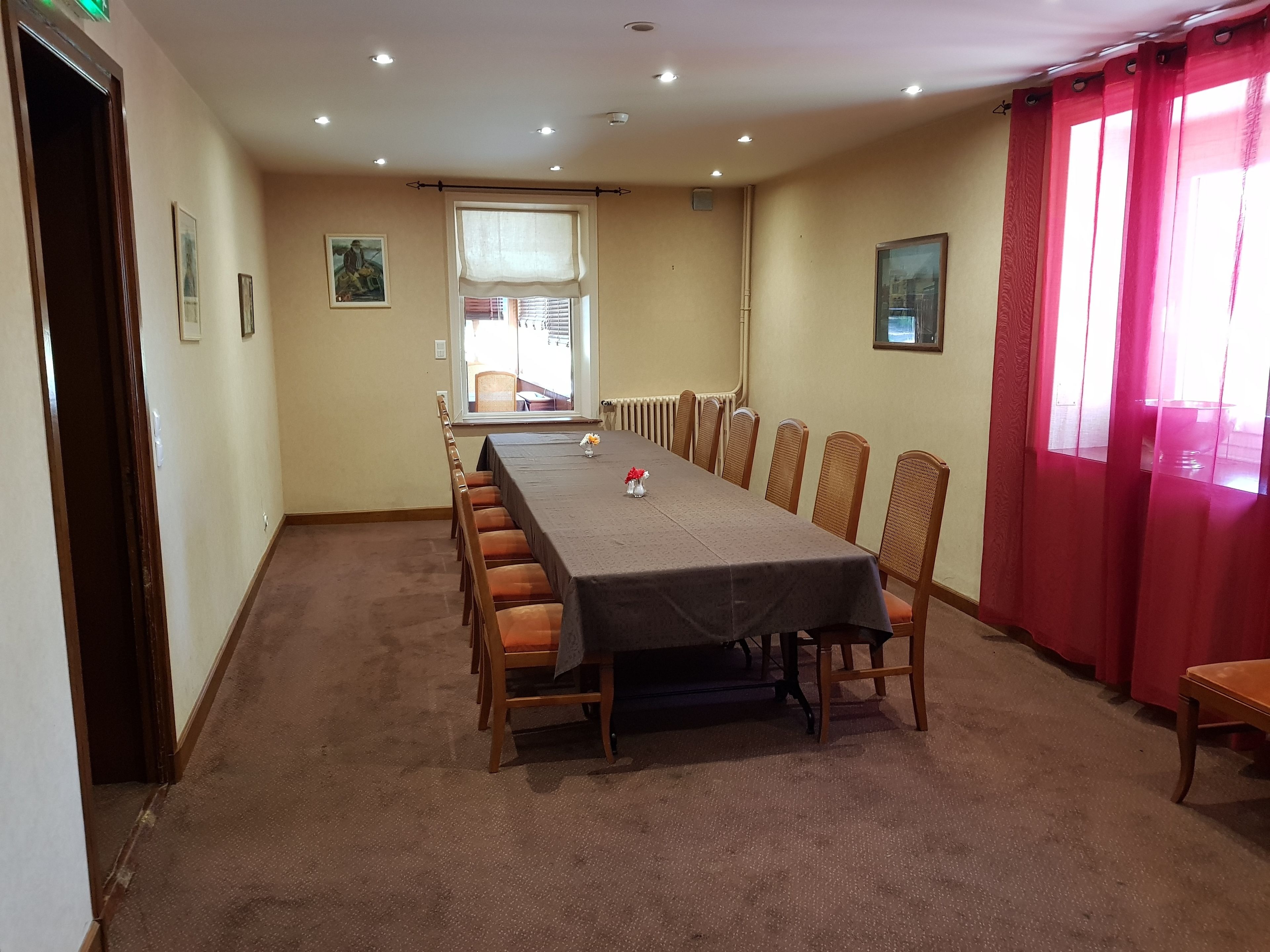 A conference room with a long table, chairs, and a window with blinds.