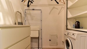 A laundry room with a washing machine, a drying rack, and a small storage cabinet. - Navona Charming Apartment (Rome)