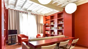 A cozy living area with a wooden table and chairs, a red bookshelf, and a television. - Navona Charming Apartment (Rome)
