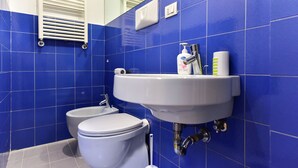 Un baño con azulejos azules, un lavabo blanco y un inodoro.