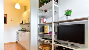 Una cocina moderna con armarios blancos, un microondas y un televisor sobre un estante blanco.
