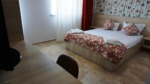 Una habitación de hotel con una cama grande, un escritorio de madera y una silla.