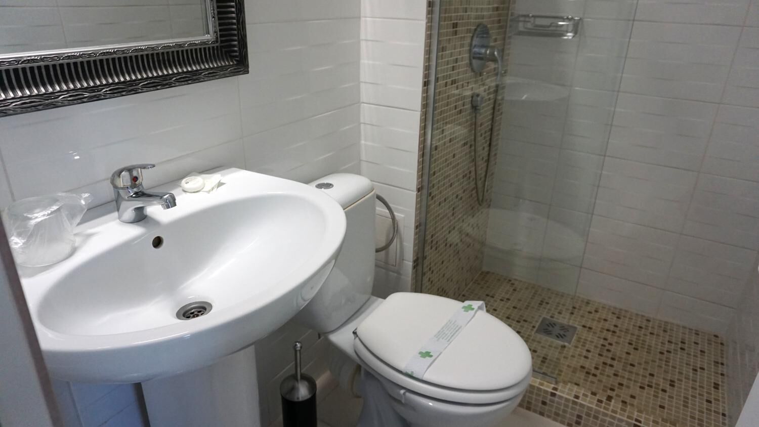 A bathroom with a white sink, toilet, and a shower area.