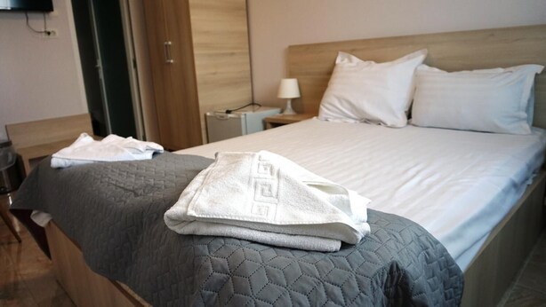 A hotel room with a bed, a nightstand with a lamp, and a wooden wardrobe. - OITUZ Boutique Residence (Mangalia)