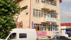 A building with a sign for 'Anna Travel' and a van parked in front. - OITUZ Boutique Residence (Mangalia)