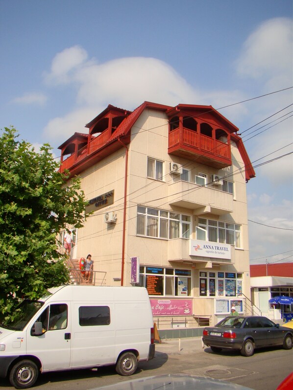 Un edificio con un letrero que dice 'Anna Travel' y una furgoneta estacionada en la calle.