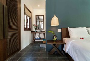 A hotel room with a bed, a nightstand, a mirror, a hanging light fixture, and a view of the hallway. - An Bang Seastar Boutique Villa (Da Nang)