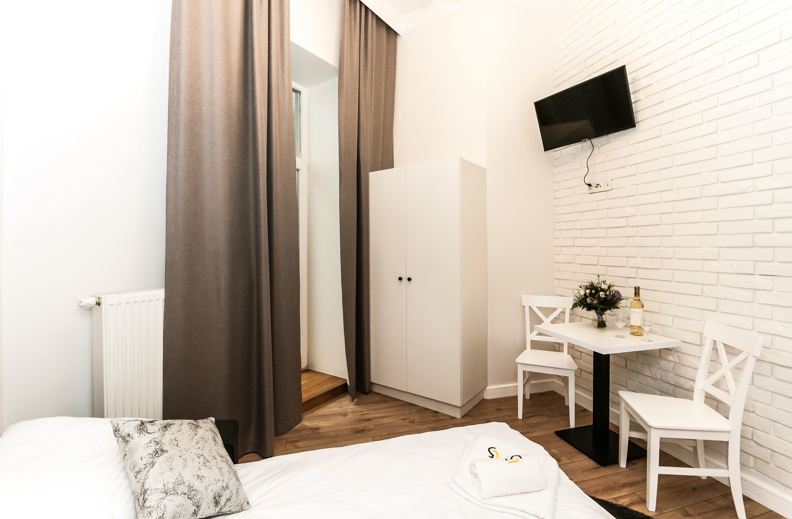 Une chambre d’hôtel comprenant un lit, un bureau avec deux chaises, un téléviseur fixé au mur et une armoire.