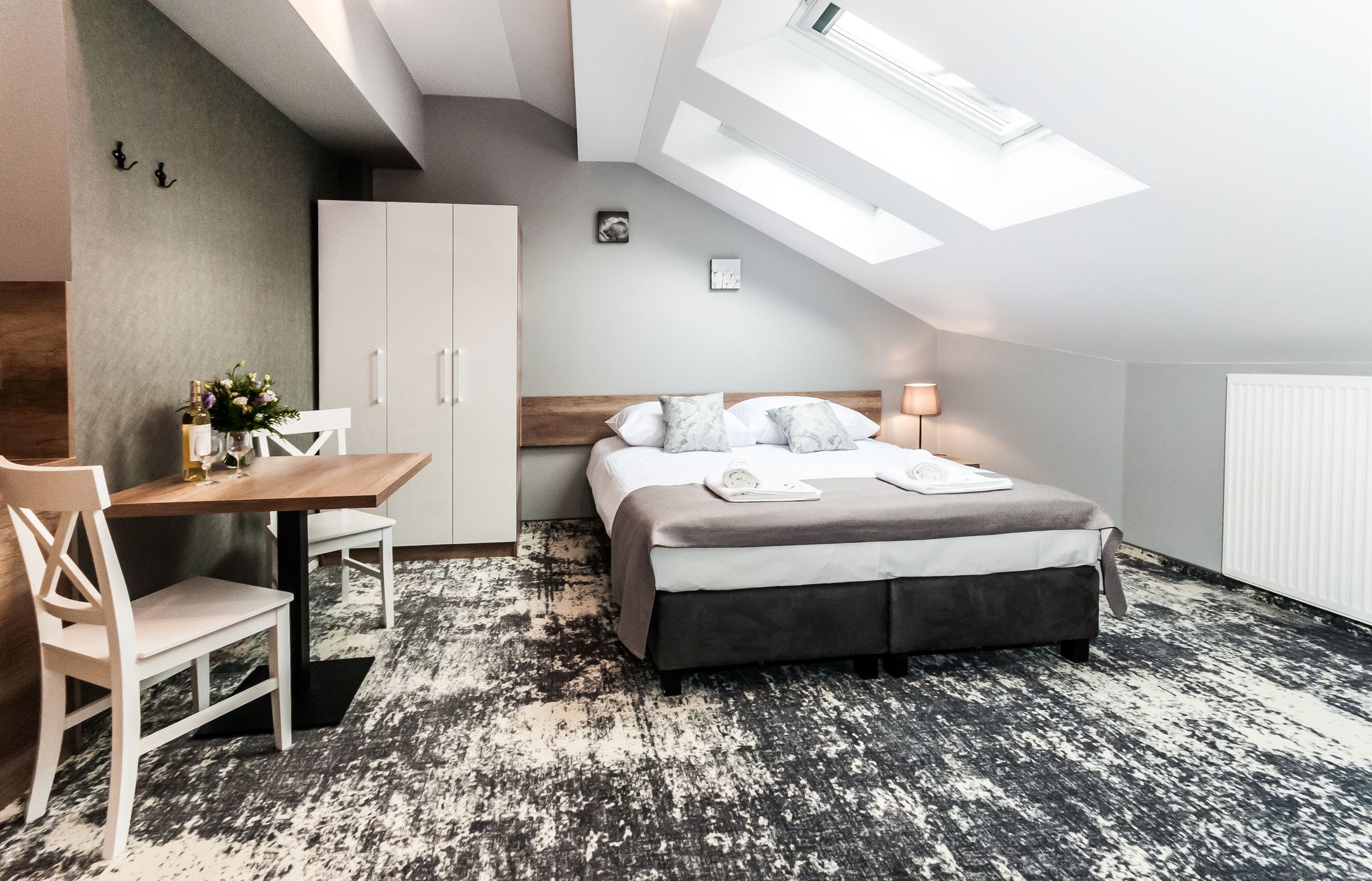 A bedroom with a bed, a desk, and a chair. There is a skylight above the bed.