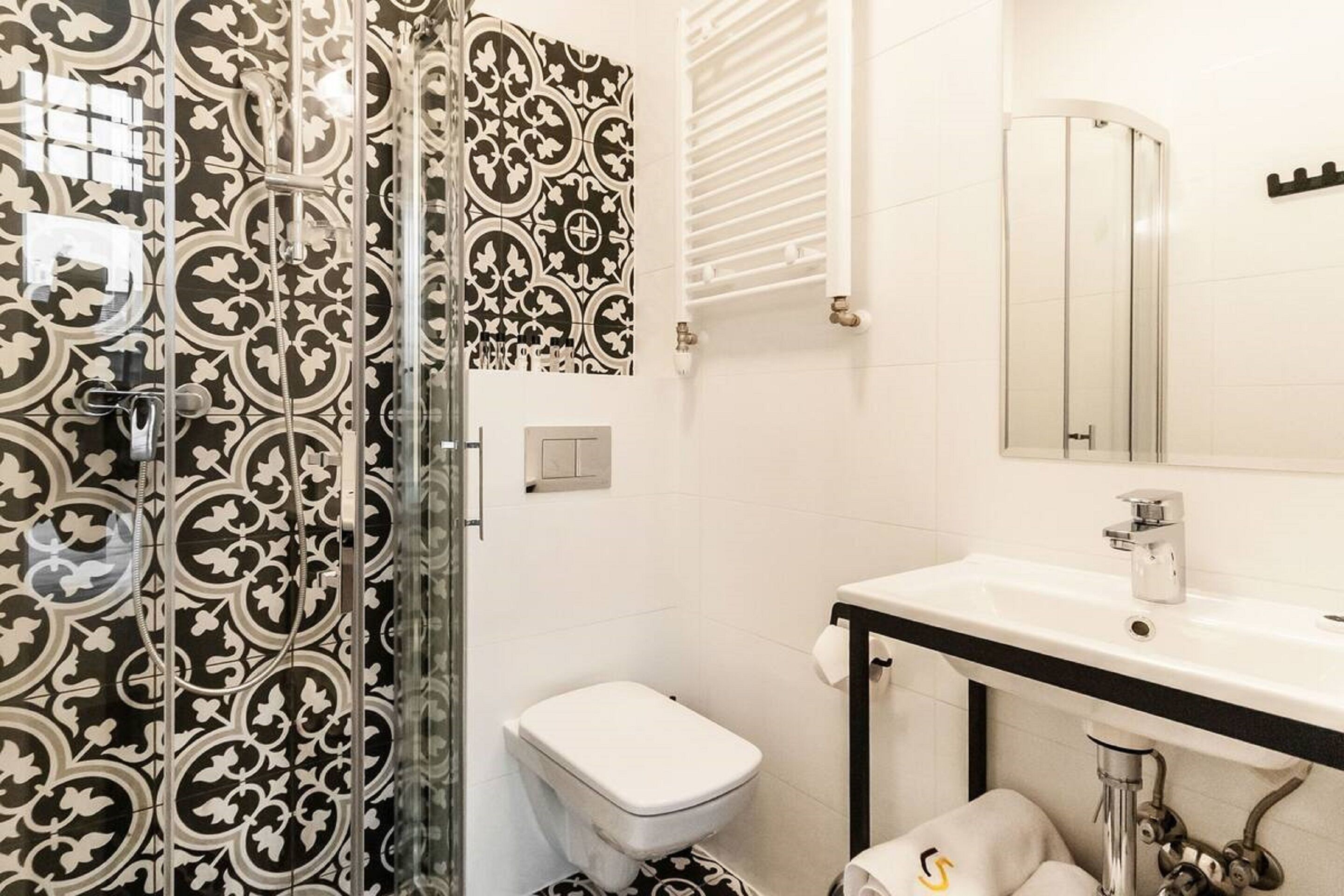 A bathroom with a shower, toilet, sink, and a mirror.