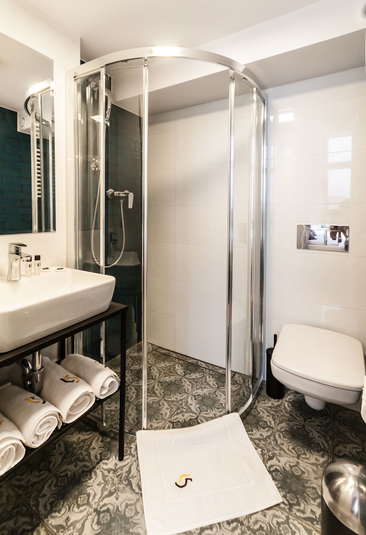 A modern bathroom with a glass-enclosed shower, a white sink, and a toilet.