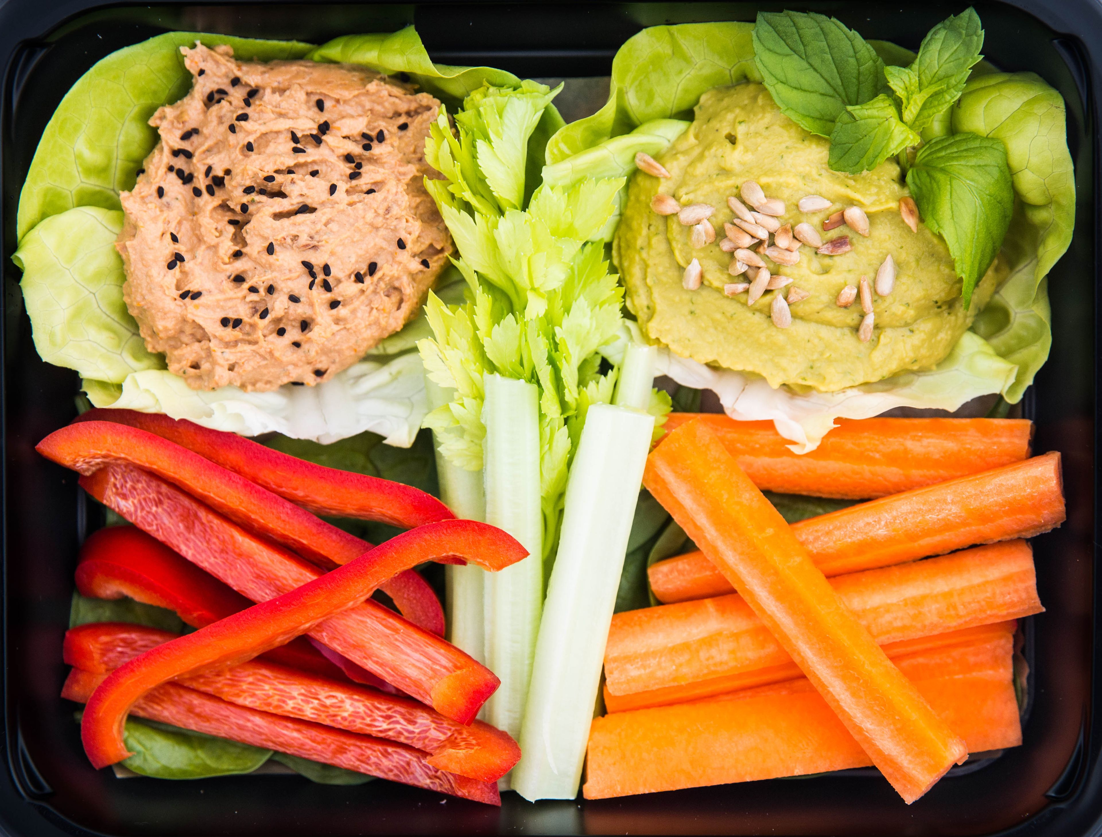 Ensalada con lechuga, zanahorias, apio y dos tipos de salsa.
