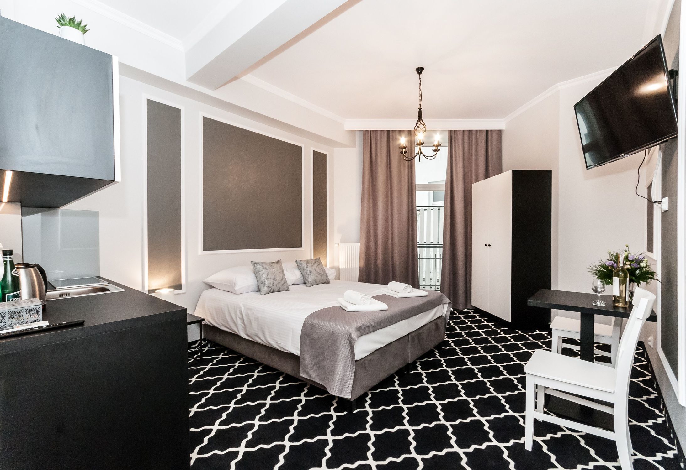 A modern hotel room with a large bed, a desk, a TV, and a view of the outdoors.