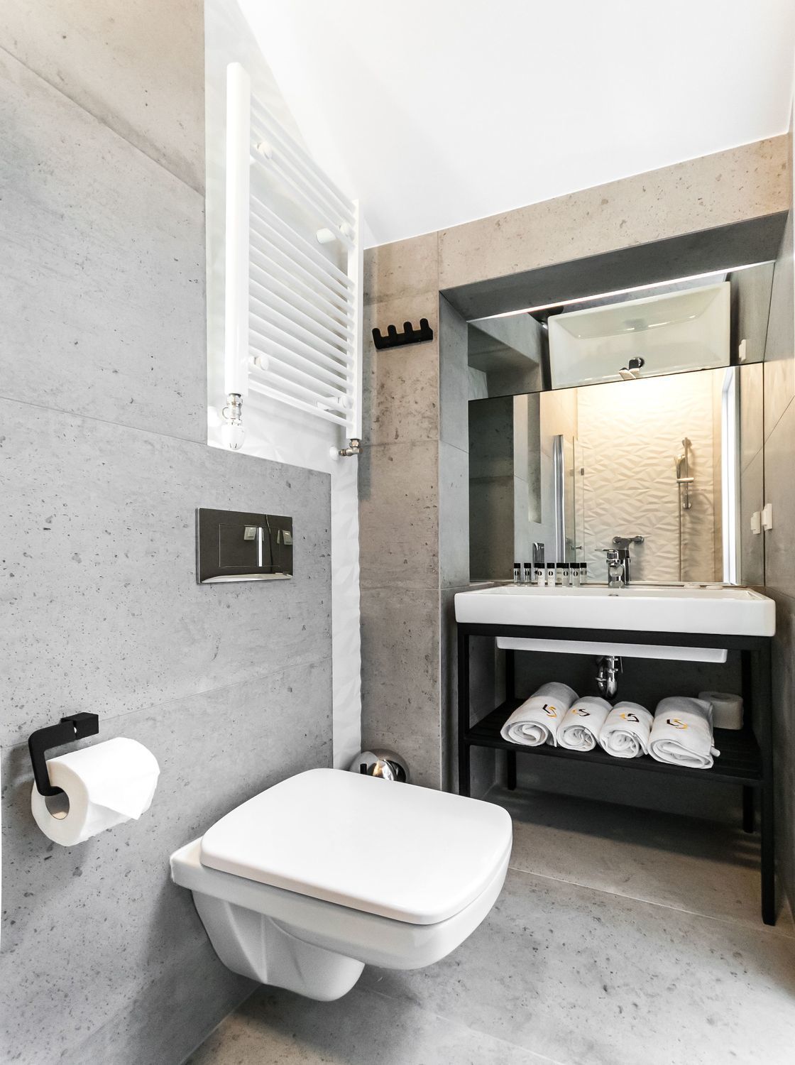 Ein modernes Badezimmer mit Toilette, Waschbecken und Handtuchhalter.