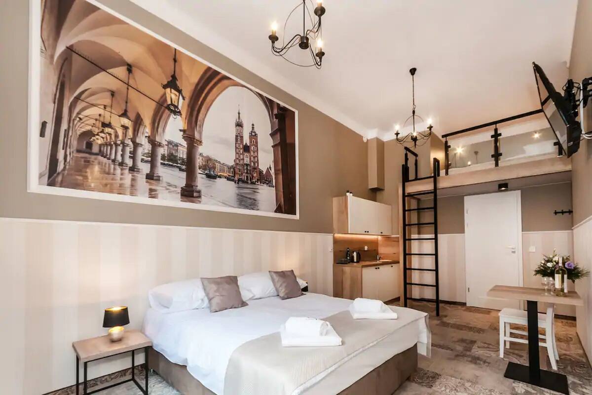 Quarto de hotel com uma cama grande, uma escrivaninha, uma cadeira, uma escada e um lance de escadas.