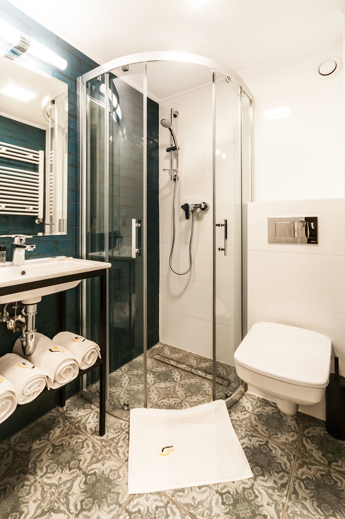 Un baño moderno con ducha de vidrio, lavamanos blanco y retrete.