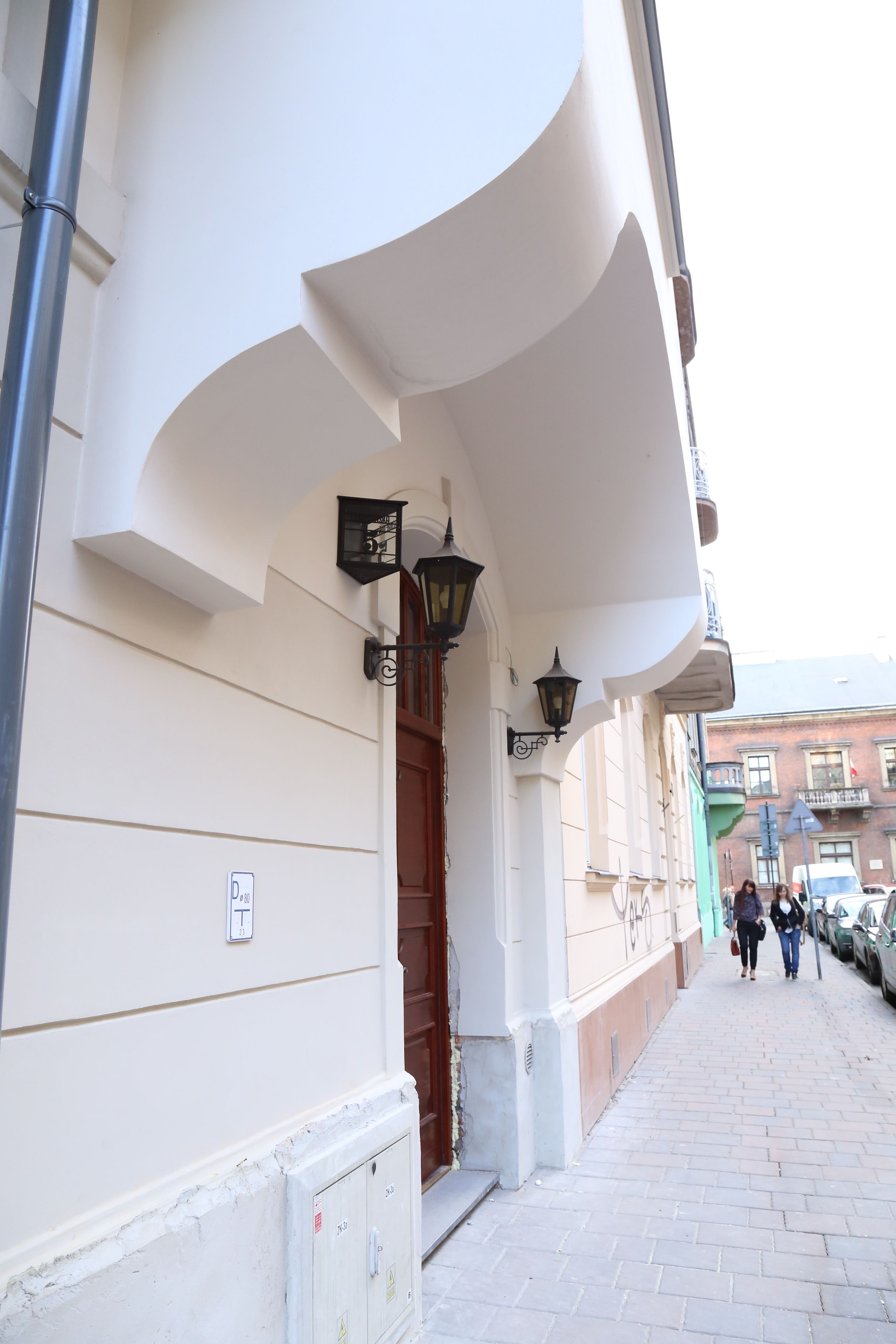 Un edificio con fachada blanca, puerta de madera y acera de ladrillo.