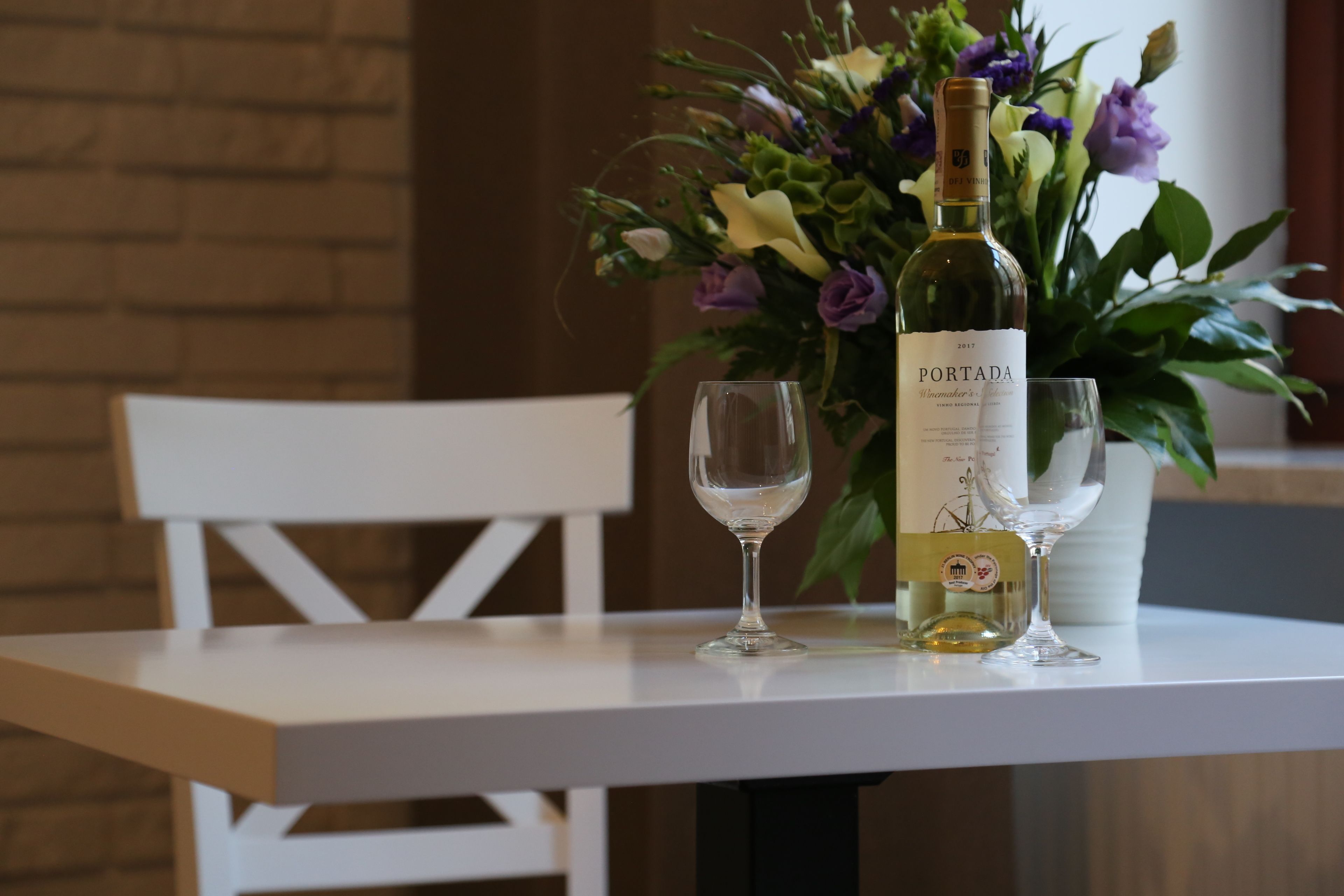 Un tavolo con una bottiglia di vino Portada, due bicchieri da vino e un vaso di fiori.