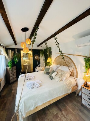 A bedroom with a large bed, hanging plants, and a wooden ceiling. - La Villa Tosca (Callas)