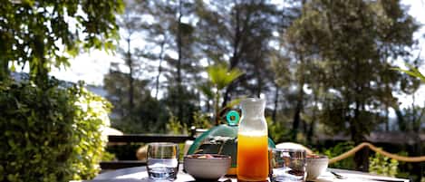 A round table with a pitcher of orange juice, a bowl, a glass, and a spoon.