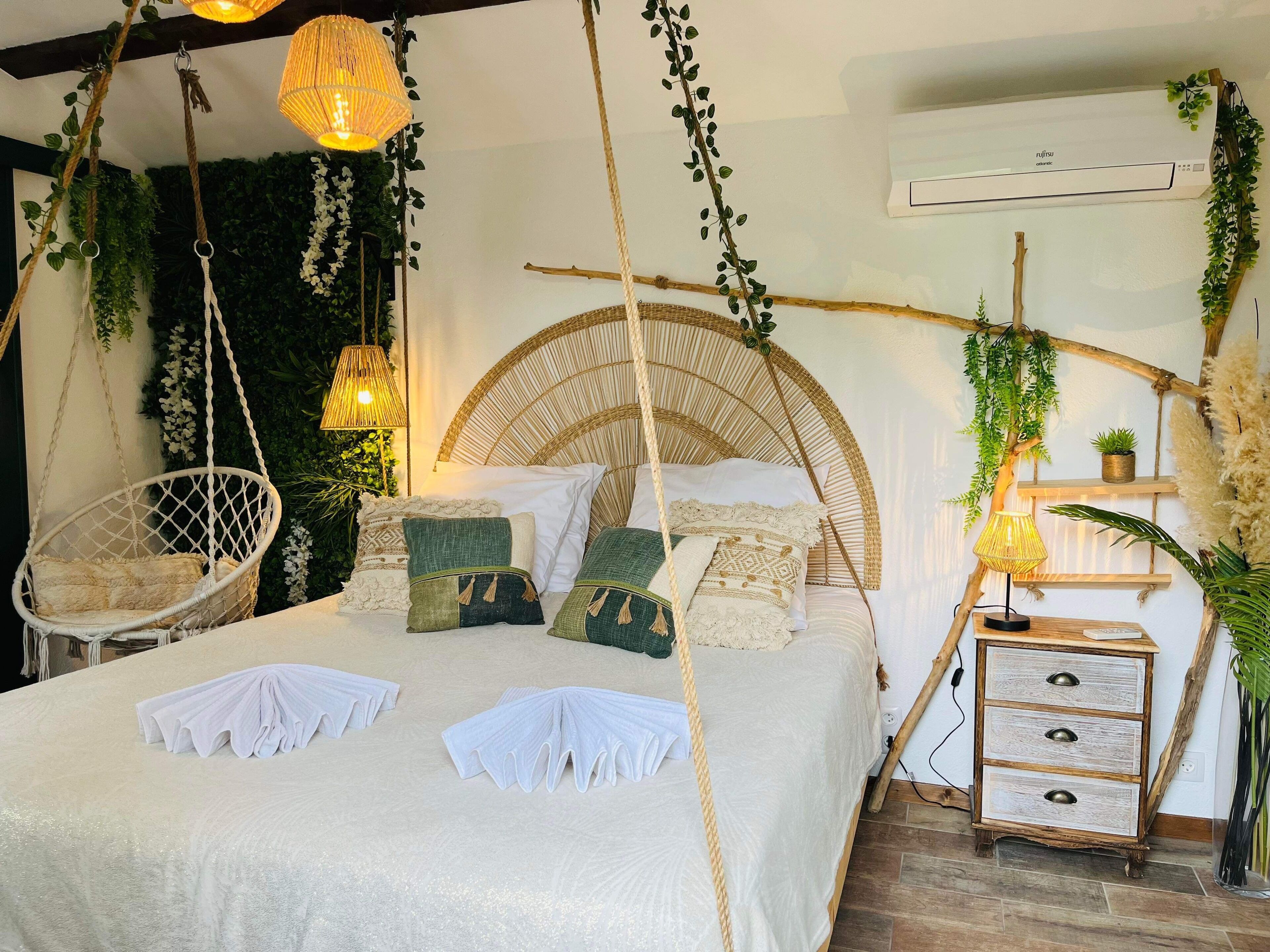 Ein Schlafzimmer mit Bett, Hängestühlen und einem Nachttisch.