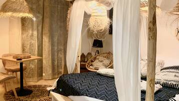 Ein Schlafzimmer mit Himmelbett, einem runden Tisch und einem Stuhl.