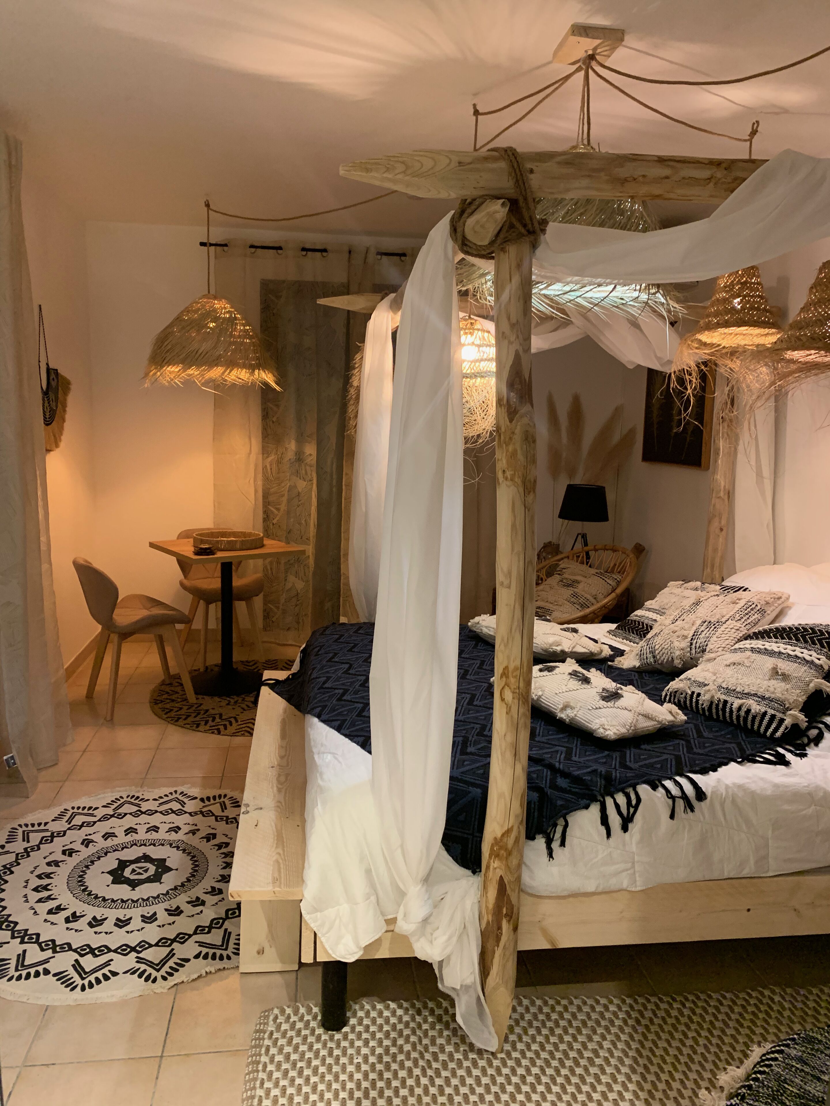 Un dormitorio con cama con dosel, una mesa de comedor redonda y una silla.