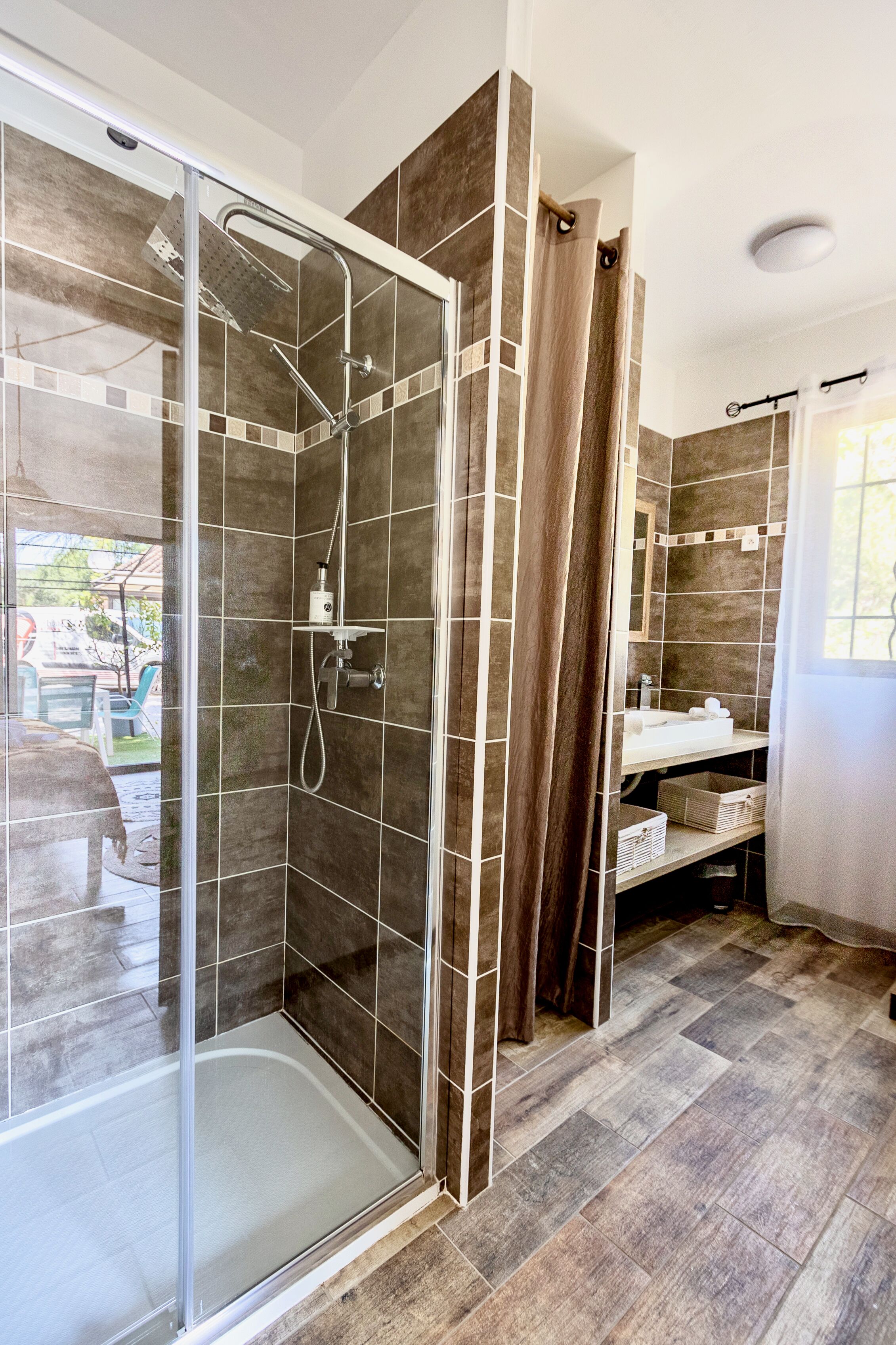 Un baño moderno con ducha envuelta en vidrio, tocador con lavabo y espejo.