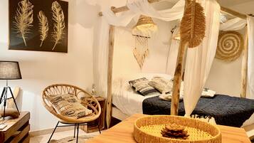Una habitación con cama, una silla, una mesa y una obra de arte colgada en la pared.