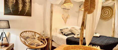 A room with a bed, a chair, a table, and a wall-mounted artwork.