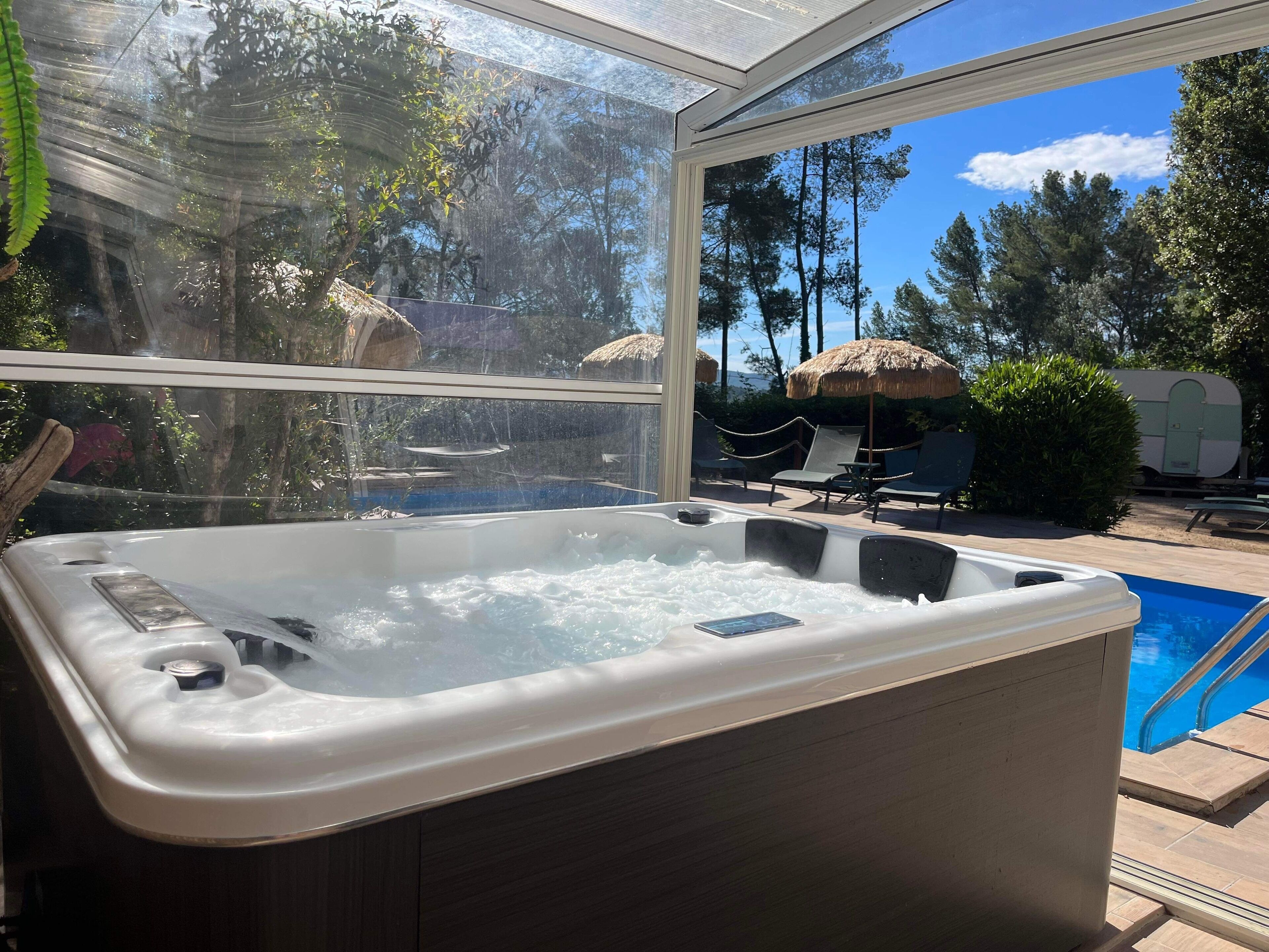 Ein Whirlpool mit Blick auf einen Pool und Sitzgelegenheiten im Freien.