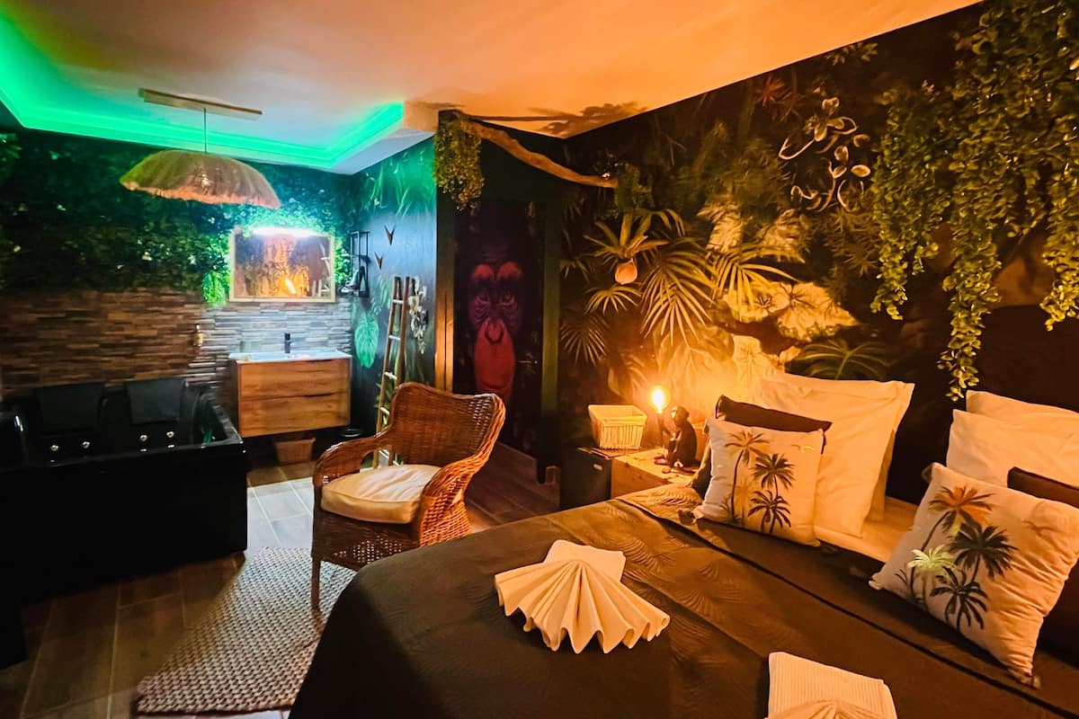A cozy bedroom with a bed, a nightstand, a lamp, and a wall mural.