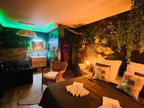 A cozy bedroom with a bed, a nightstand, a lamp, and a wall mural. - La Villa Tosca (Callas)