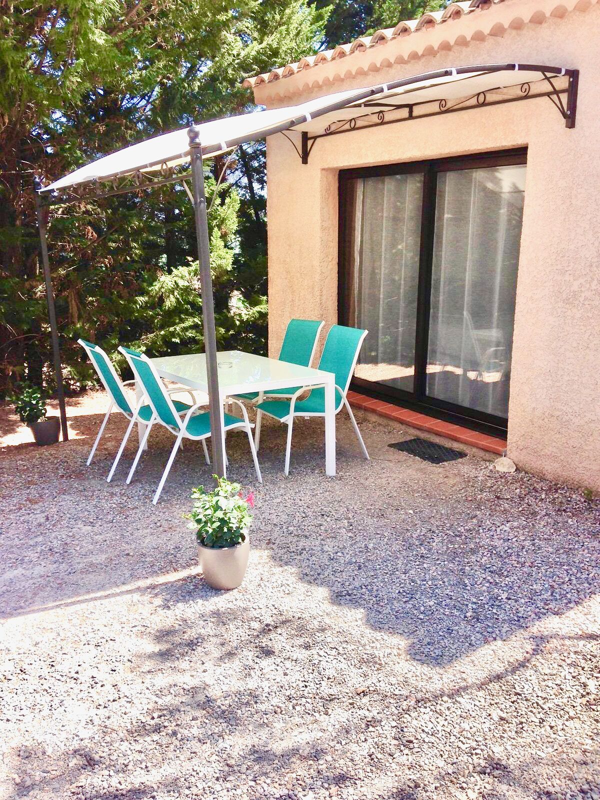 Un patio al aire libre con una mesa y sillas, una pérgola y una puerta corrediza de vidrio.