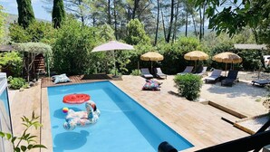 Ein Swimmingpool mit einer Schwane als Schwimmspielzeug, Liegestühlen und Sonnenschirmen.
