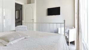 A bedroom with a bed, a TV mounted on the wall, a chair, and a window with curtains. - Pantheon Cozy Apartment n. 4 (Rome)