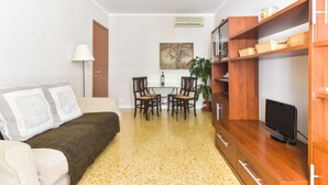 A compact living space with a sofa, a dining table with chairs, a TV on a wooden stand, and a potted plant. - Pantheon Cozy Apartment n. 4 (Rome)